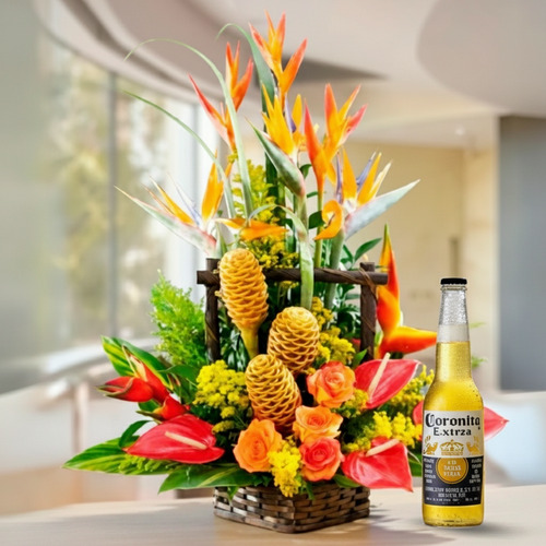 Arreglo floral tropical en canasta de mimbre con flores exóticas de colores amarillo, naranja y rojo junto a una botella de cerveza Coronita Extra sobre fondo interior desenfocado