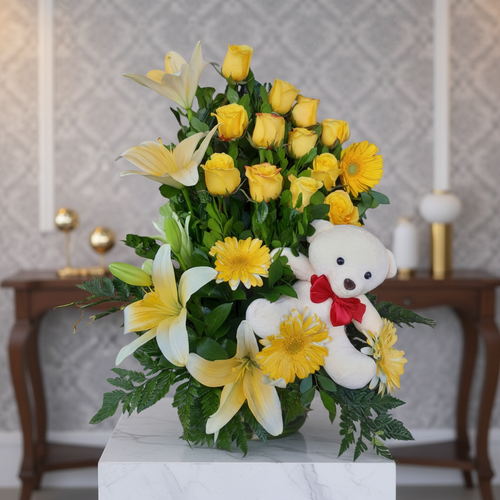 Arreglo floral con rosas amarillas y oso de peluche blanco arreglo floral con rosas amarillas, gerberas y lirios blancos acompañado de un oso de peluche blanco con moño rojo sobre pedestal de mármol