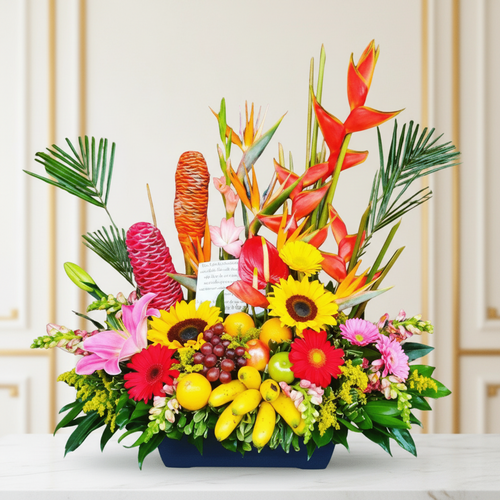Arreglo de flores tropicales y frutas frescas en base azul Centro de mesa con flores tropicales de colores vivos y frutas variadas sobre fondo interior elegante