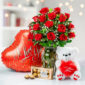 Ramo de rosas rojas en jarrón de cristal junto a globo rojo en forma de corazón con texto I Love You, oso de peluche blanco con corazón rojo y caja de chocolates Ferrero Rocher