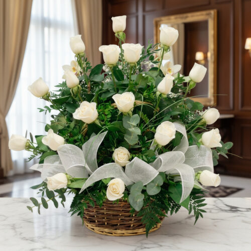 Arreglo floral de rosas blancas y orquídeas en una cesta de mimbre con lazo blanco, sobre una mesa de mármol en un entorno el
