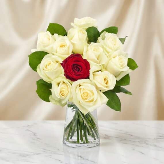 Arreglo Floral CARLA: Diseño Premium con 12 Rosas de Tallo Largo Arreglo floral CARLA con 12 rosas de tallo largo, una roja central y once blancas, en un jarrón de cristal sobre mármol.