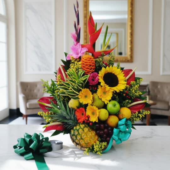 Arreglo floral exótico Antídoto con girasoles, aves del paraíso, piña, uvas y manzanas, sobre mármol blanco en un lobby elega