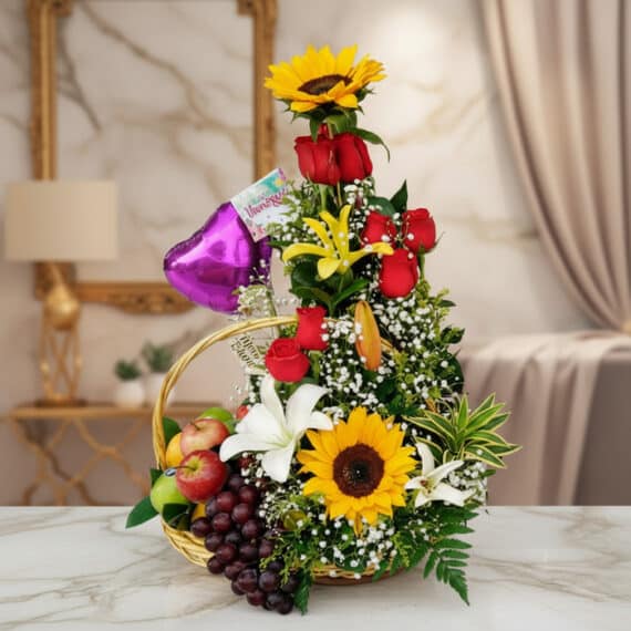 Arreglo floral Capella con girasoles, rosas rojas, lirios blancos y amarillos, y follaje verde, acompañado de una cesta con u