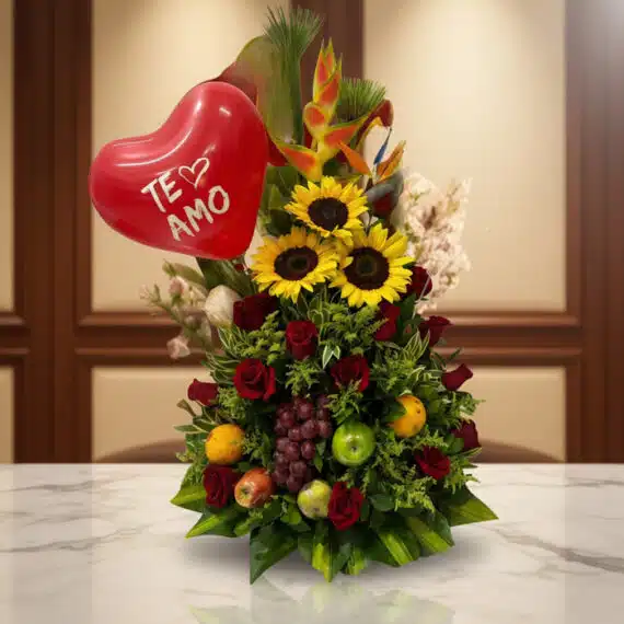 Arreglo Floral con Frutas Trópico: Elegancia y Frescura para Regalar Arreglo floral premium con girasoles, rosas rojas, frutas tropicales (uvas, manzanas, naranjas) y un globo rojo de corazón co