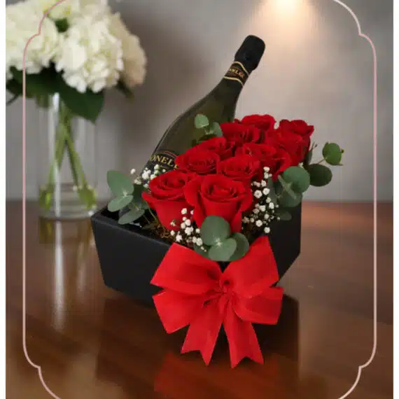 Arreglo Floral NATALE: Rosas Rojas y Vino, Regalo Elegante Arreglo floral NATALE con rosas rojas frescas, vino espumoso y lazo rojo en caja negra, ideal para regalo elegante.