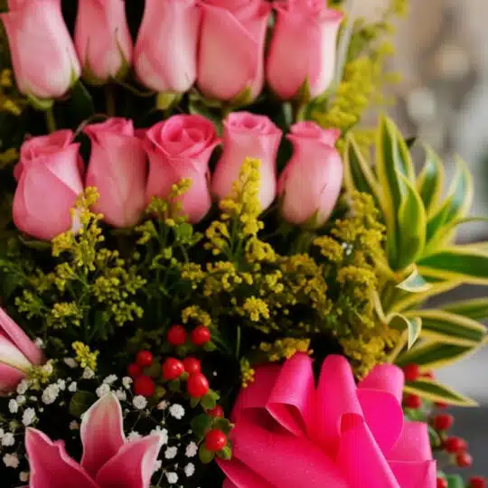 Primer plano extremo de Arreglo Floral Quiero que Sepas, mostrando rosas rosadas, lirios, bayas rojas y follaje verde con got