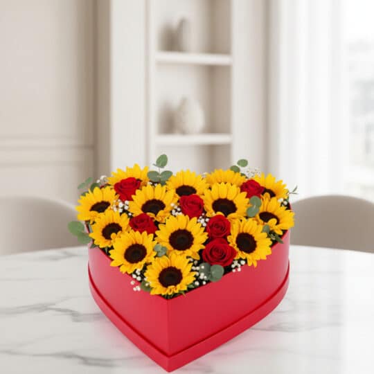 Arreglo floral RINA en forma de corazón con girasoles vibrantes y rosas rojas, ideal para expresar amor y alegría en cualquie