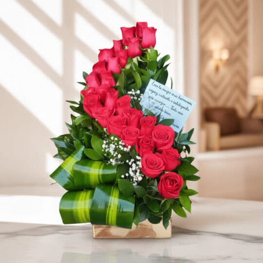 Arreglo floral premium con rosas rojas voluta, follaje verde y detalles blancos, sobre una superficie de mármol en un entorno