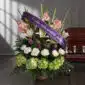 Arreglo floral fúnebre 'Te Fuiste' con lirios blancos, gladiolos rosados y hortensias verdes, adornado con una cinta morada d