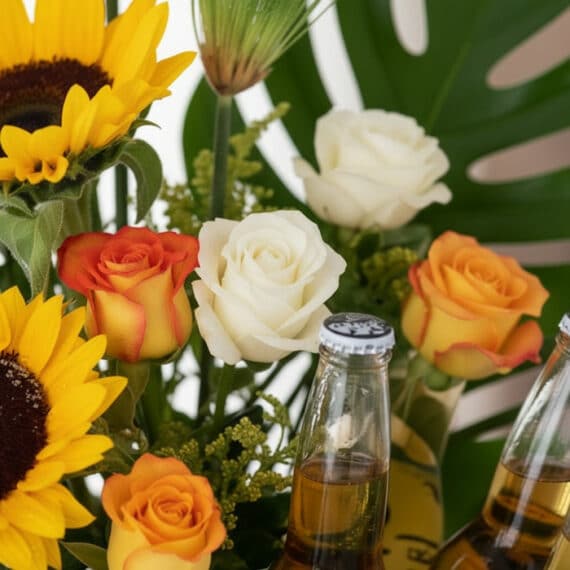 Primer plano extremo de Arreglo con Girasoles Temis, mostrando girasoles, rosas blancas y naranjas, y botellas de cerveza con