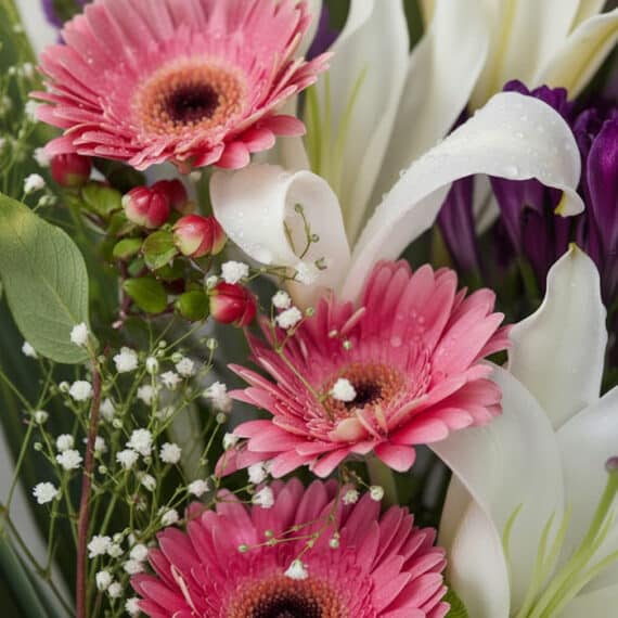 Primer plano extremo de un Bouquet GIA con gerberas rosadas, lirios blancos y flores moradas, mostrando texturas hiperrealist