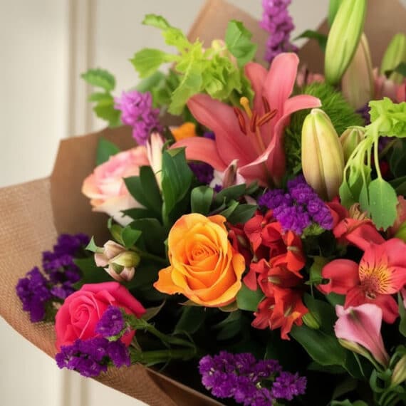 Primer plano extremo del Bouquet SOFIA con rosas, lirios y flores primaverales, textura hiperrealista, gotas de rocío, colore