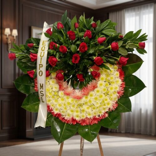 Corona fúnebre Adiós Sincero con rosas rojas y flores blancas, en una sala de velación premium con luz natural suave y bokeh.