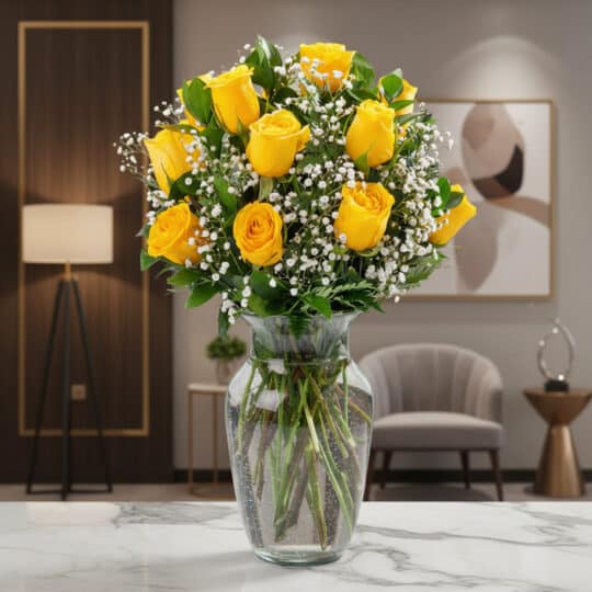 Jarrón de cristal con doce rosas amarillas vibrantes y follaje verde, sobre una superficie de mármol en un entorno de lujo.